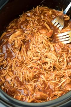 a fork is being used to stir noodles in the slow cooker with meat sauce