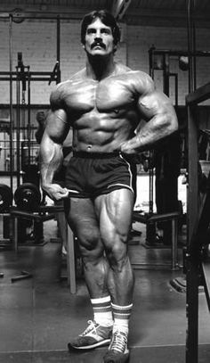 a man standing in the middle of a gym with his hands on his hips and looking at the camera