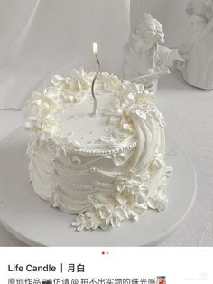 a white cake sitting on top of a plate with a candle in the middle of it