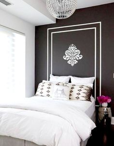 a bedroom with black walls and white bedding, chandelier over the headboard