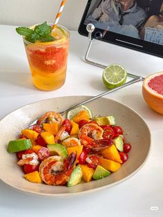 there is a plate of food and a drink on the table with a computer in the background