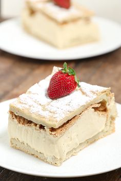 two plates with desserts on them and one has a strawberry in the middle, while the other is topped with powdered sugar