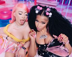 two women with pink hair and black bras posing for the camera, one is sticking her tongue out