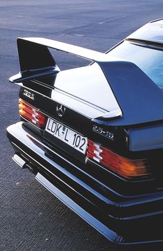 the rear end of a black car parked in a parking lot with its hood down