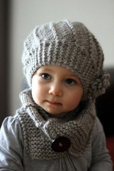 a baby wearing a knitted hat and scarf with buttons on it's neck