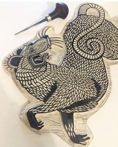 an intricately carved wooden carving of a bird on a white surface with a black marker