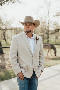 a man wearing a cowboy hat standing in front of a zebra