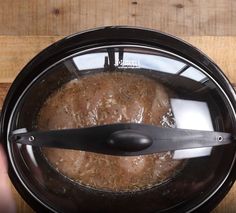 a person is holding a spoon in an air frying pan with meat on it