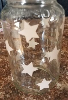 a glass jar sitting on top of a counter with white stars painted on the lid