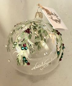 a glass ornament with holly and berries on it