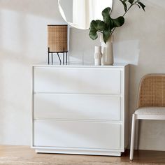 a white dresser sitting next to a mirror on top of a wooden floor