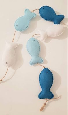 three blue and white stuffed animals hanging from twine with string attached to each one