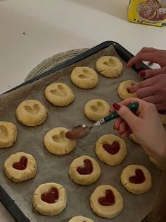 someone is making heart shaped cookies on a baking sheet