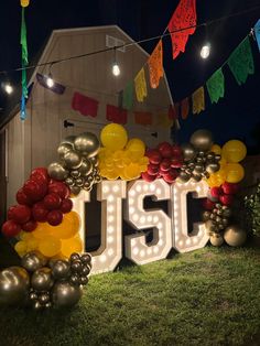 the letters j s c are lit up with balloons and streamers in front of a barn