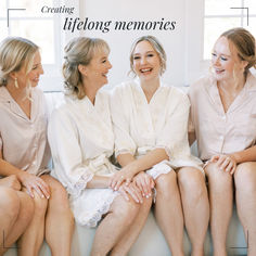 four women in robes sitting on a couch laughing and looking into each other's eyes