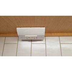 an electronic device is mounted on the wall in front of tile flooring and wood paneling