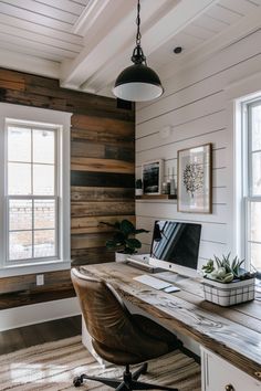 a home office with wood paneling on the walls and a leather chair in front of it