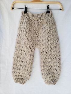 crocheted baby joggers with a high waist.  there is a drawstring for the waist to make them as snug as necessary.  the stitch pattern matches the cross-body sweater listed in my store and the two together would make a darling set. {https://www.etsy.com/listing/674394330/crocheted-cross-body-sweater-crocheted?ref=shop_home_active_3&frs=1} these pants are size 18 to 24 month. these pants are made with 100% taupe, acrylic yarn.  this item is made in a clean, smoke and pet free environment. pants can be machine washed in cold water on a gentle cycle.  they can be machine dried, however i suggest drying them by laying them flat. these pants can be made from size 3-6 month to 3T/4T.  they can be made in any color you can imagine, as long as they make yarn in that color. i am more than willing, h Crocheted Cross, Pants Crochet, Crochet Baby Pants, Baby Sweatpants, Tie Waist Pants, Baby Jogger, Crochet Cross, Baby Pants, Gender Neutral Baby