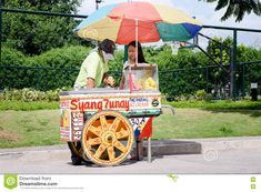 a man and woman are selling food from a cart with an umbrella on the street