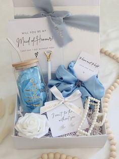 a gift box filled with blue and white items next to a bead necklace on a table