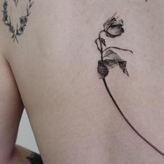 a woman's back with a single rose tattoo on her left side ribcage