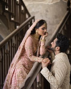 a man and woman standing next to each other in front of a stair case,