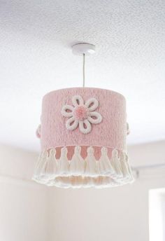 a pink lamp shade hanging from a ceiling