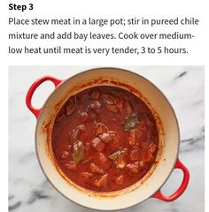 a red pot filled with food sitting on top of a table next to a white counter