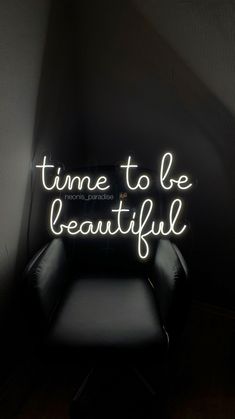 a neon sign that says time to be beautiful on a chair in a dark room