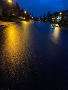 an empty street at night with the lights on and rain coming down from the sky