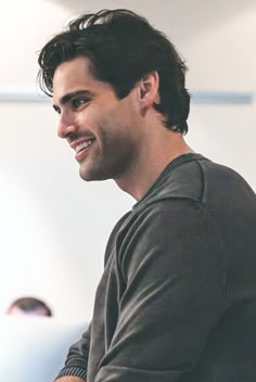 a man smiles as he sits in front of a computer screen and looks off to the side