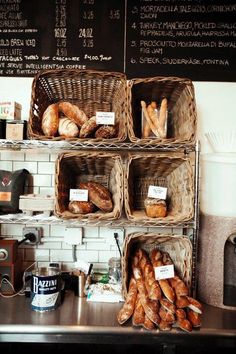 breads and pastries are displayed in baskets on the counter