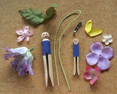 three wooden peg dolls sitting on top of a table next to purple flowers and leaves