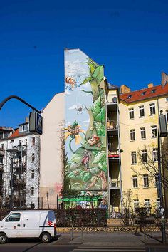 a white van parked in front of a building with a mural on it's side