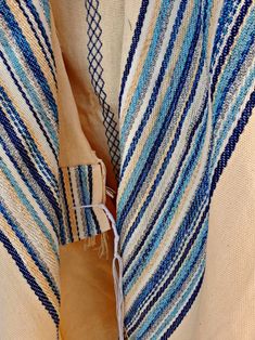 a blue and white striped shawl with tassels hanging from it's side