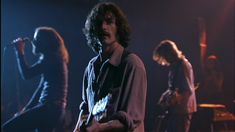 a man standing in front of a group of people on stage with guitars and microphones