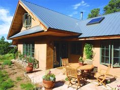 an outdoor patio with chairs and tables in front of a house that has a metal roof