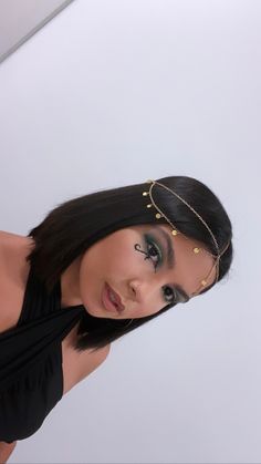 a woman with black hair and gold jewelry on her head is posing for the camera