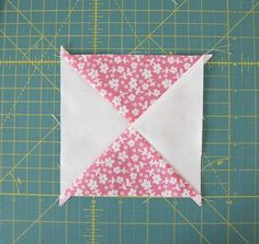 a pink and white flowered square on a green cutting board