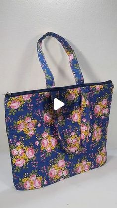 a blue floral bag with pink flowers on it and a white wall in the background