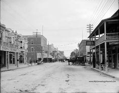 an old black and white photo of people walking down the street in front of buildings