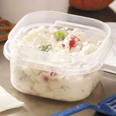 a plastic container filled with food sitting on top of a table next to a fork