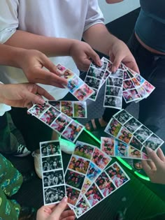 several people are holding up polaroid photos with green light in front of them on a table