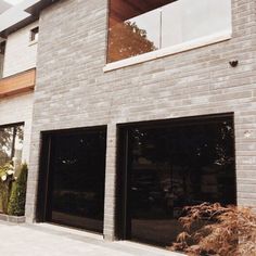 two garage doors are open in front of a brick building that has windows on each side