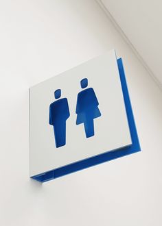 a blue and white sign hanging from the side of a wall next to a toilet