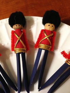 four small wooden toy soldiers sitting on top of a white plate