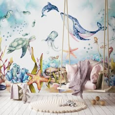 a child's room with sea animals painted on the wall and hanging from swings