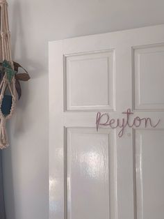 a white door with some pink letters on it and a rope hanging from the side