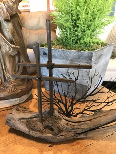 a cross sitting on top of a wooden table next to a potted planter