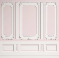 an empty room with pink walls and white frames on the wall, as well as a bench